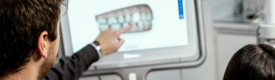 Dentist Lawrenceville GA Crowns Bridges Focused dentist is seen pointing at a digital image of a mouth scan where a bridge is needed