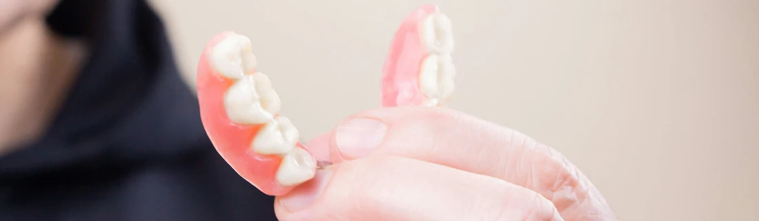 Dentist Lawrenceville GA Dentures Focused close up of a man holding dentures he's about to put in