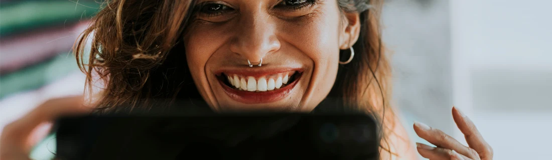 Dentist Lawrenceville GA Invisalign Focused a woman with a septum piercing smiling while on her phone